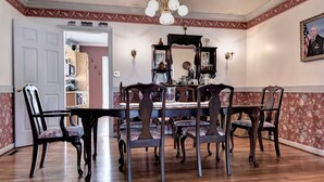 Uma sala de jantar com uma mesa e cadeiras de madeira, um candelabro e um espelho sobre a mesa.