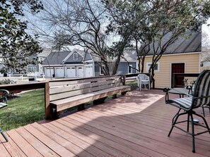 A wooden deck with a bench and chairs, surrounded by trees and houses. - Aldrich House Bed & Breakfast (Williamsburg)
