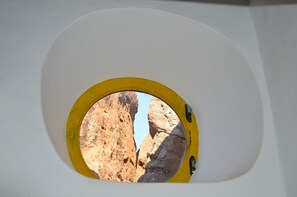 A circular window with a yellow frame, revealing a rocky canyon view. - Appartamento Zeus (Lipari)