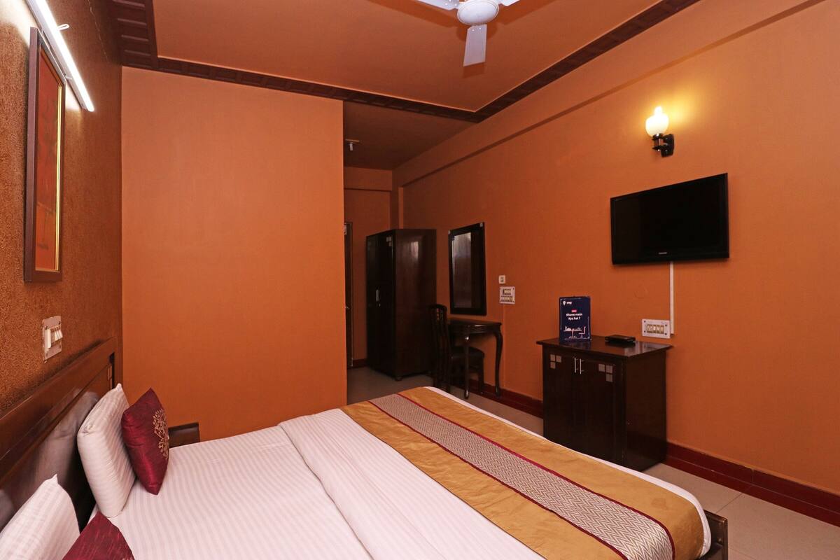 A hotel room with a bed, a television mounted on the wall, and a desk with a chair.