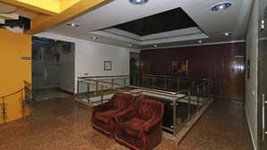 A lobby with a glass railing, two velvet armchairs, a marble floor, and a ceiling with recessed lighting. - OYO 6590 Hotel Amaraa (Gurugram)