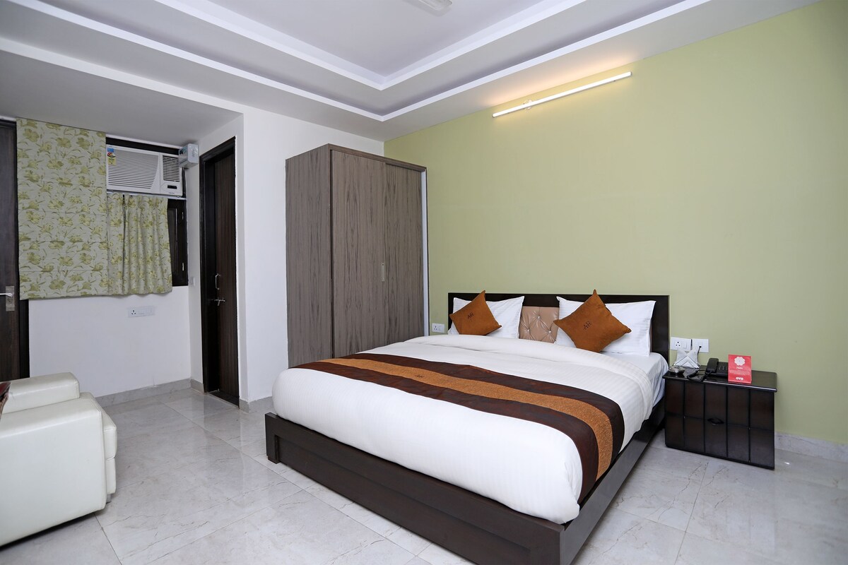 A hotel room with a bed, a wardrobe, a nightstand, and a seating area.