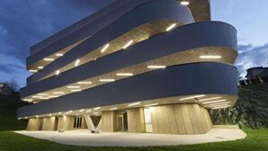 Un edificio moderno con una arquitectura curva distintiva y varios niveles iluminados.