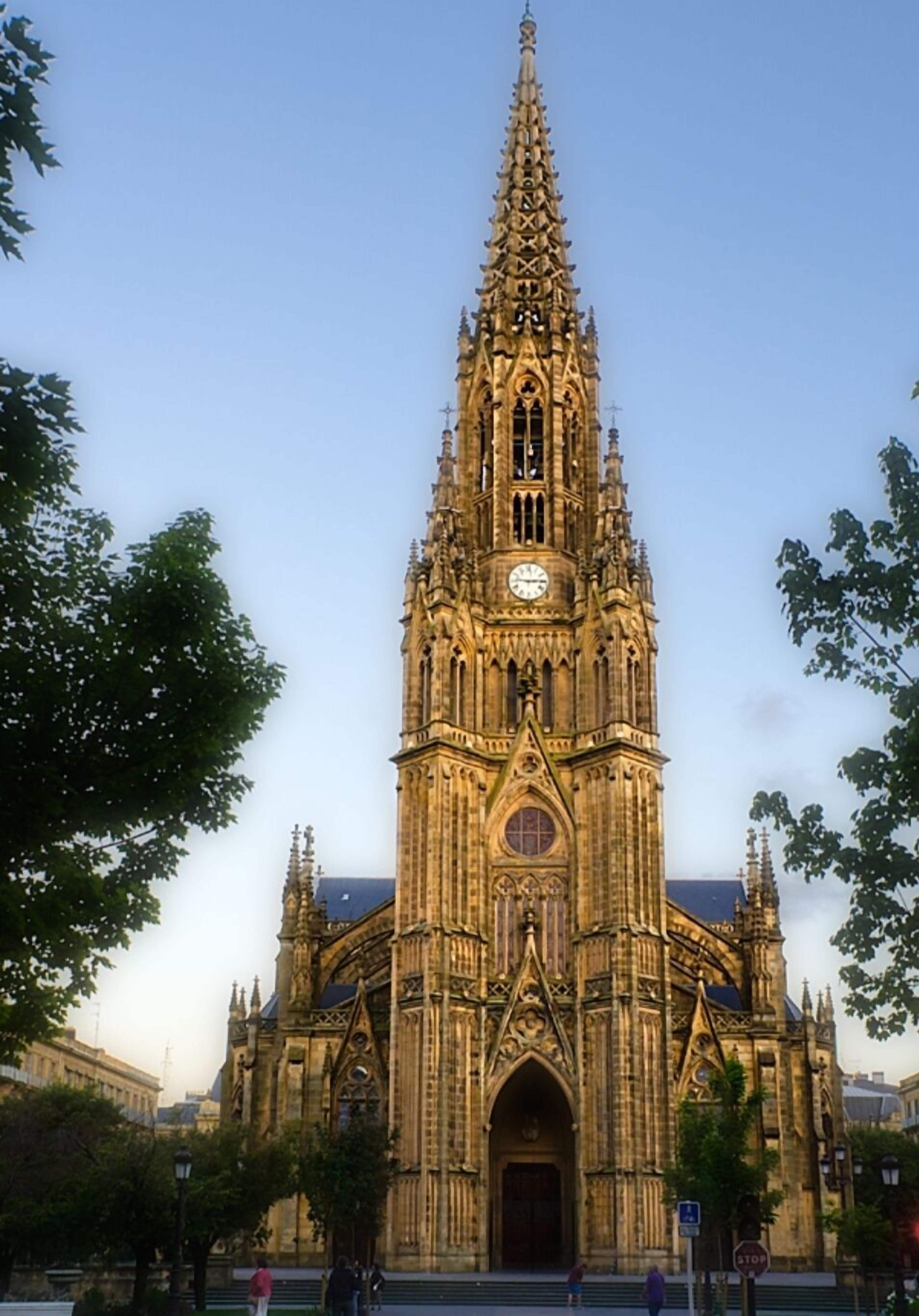 A large, ornate cathedral with a tall spire, a clock, and a large arched entrance.