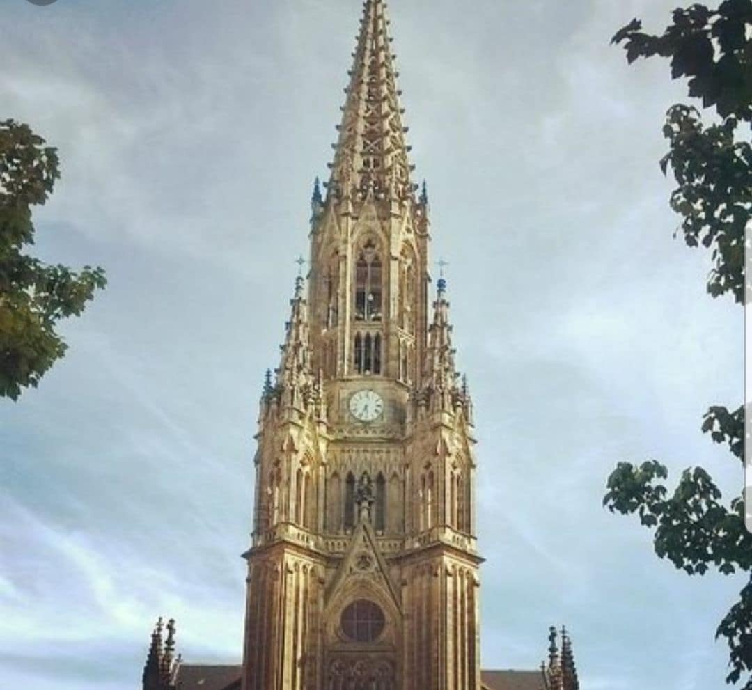 Una alta y ornamentada torre de iglesia con un reloj.