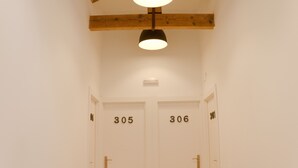 Un pasillo con dos puertas indicadas con los números 305 y 306, vigas de madera en el techo y una lámpara arriba.