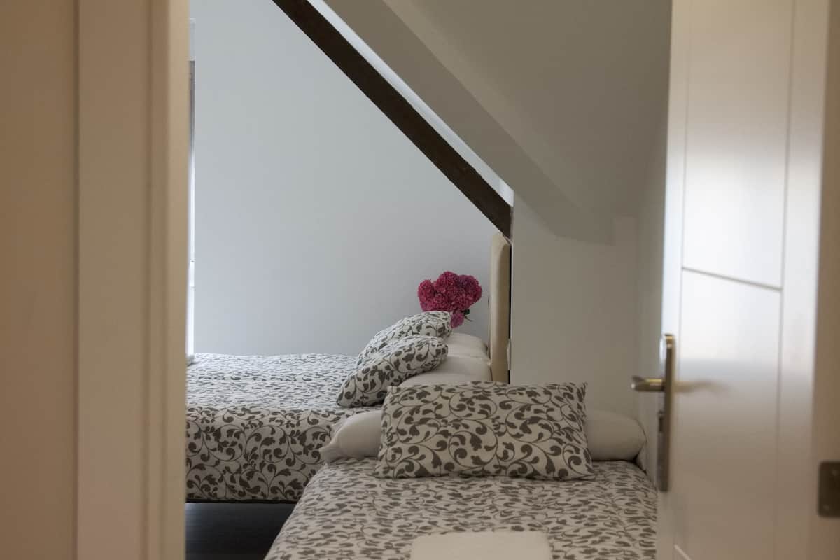 Une chambre avec deux lits, une tête de lit en bois et une décoration florale rose.