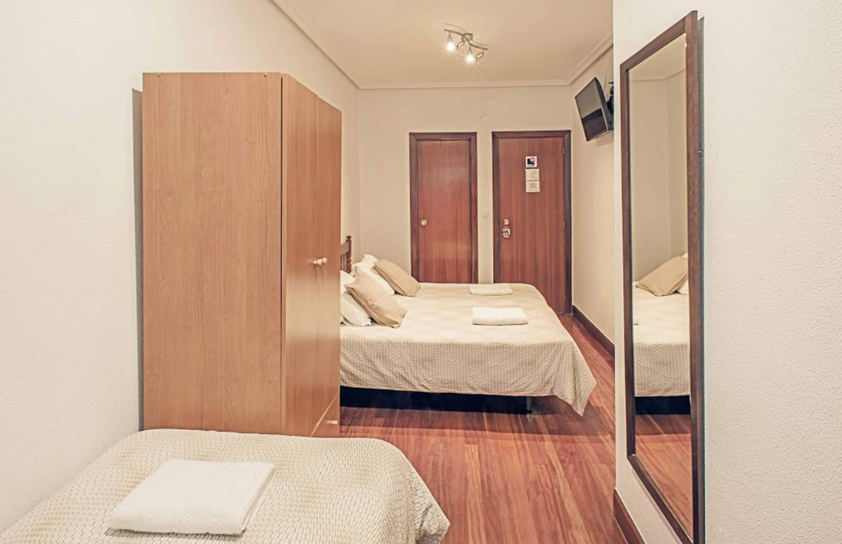 Ein Hotelzimmer mit zwei Betten, einem Schrank, einem Spiegel und einer Tür mit einem Schild.