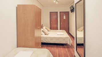 Ein Hotelzimmer mit zwei Betten, einem Schrank, einem Spiegel und einer Tür mit einem Schild.