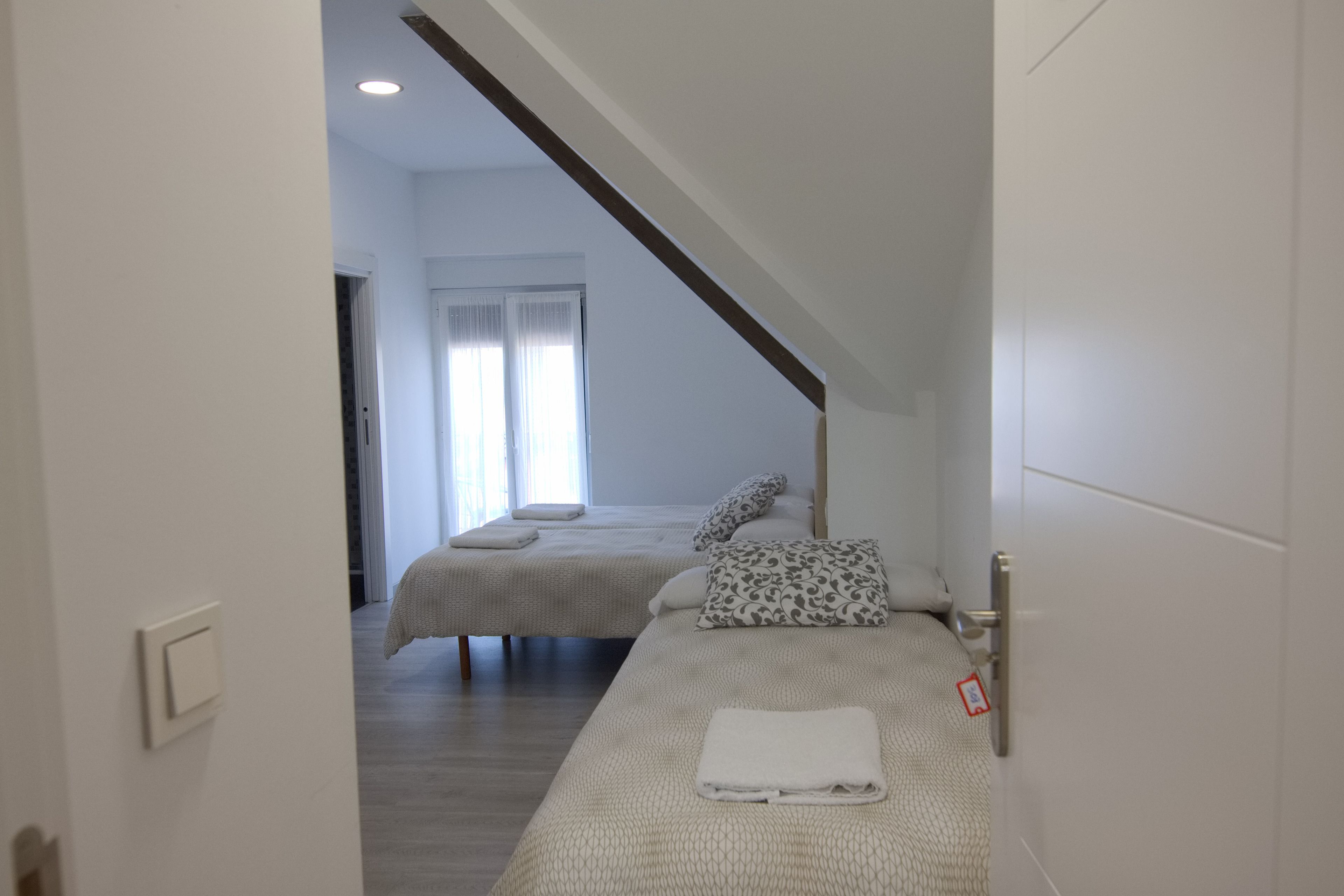 Habitación de hotel con dos camas, una viga de techo de madera y una ventana con cortinas.