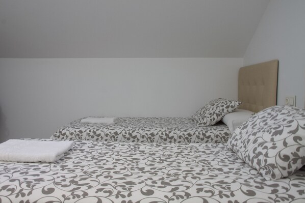 A bedroom with two beds, each with patterned bedding and pillows. - Pension Beizama (Astigarraga)