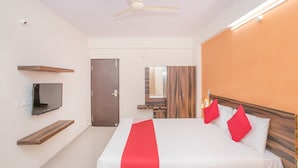 A hotel room with a bed, a TV, a ceiling fan, and a wooden headboard. - OYO 10475 PMR Hotel (Bengaluru)