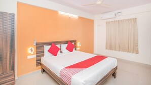 A hotel room with a bed, a ceiling fan, an air conditioning unit, and a window with curtains. - OYO 10475 PMR Hotel (Bengaluru)