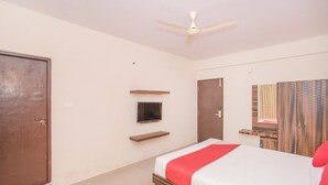 A bedroom with a bed, a ceiling fan, a wardrobe, and a television on the wall. - OYO 10475 PMR Hotel (Bengaluru)