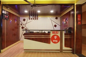 A reception desk with a digital clock, a ceiling fan, and a sign indicating 'OYO Rooms'. - OYO 10551 Hotel RJ Grand (Coimbatore)