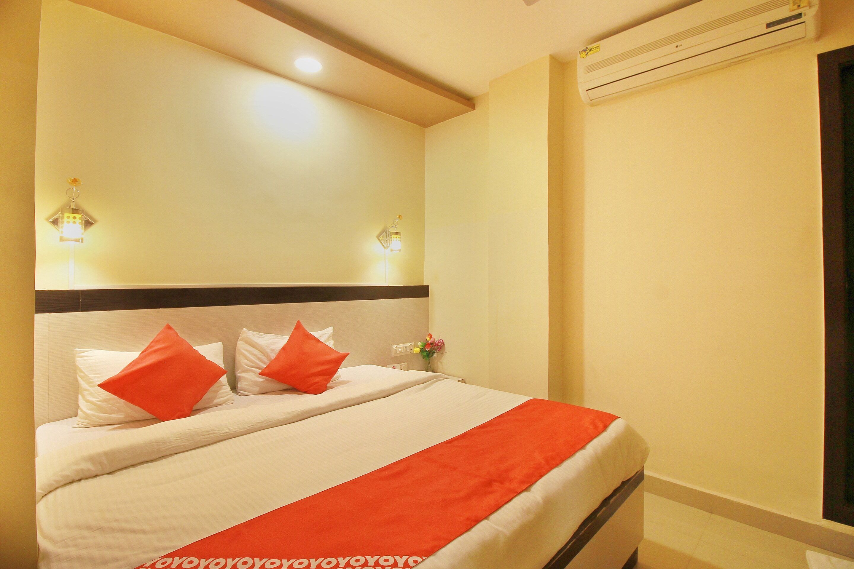 Habitación de hotel con una cama, dos lámparas de pared, aire acondicionado y una ventana.