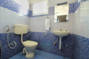 A bathroom with a toilet, sink, and mirror. - OYO 10551 Hotel RJ Grand (Coimbatore)