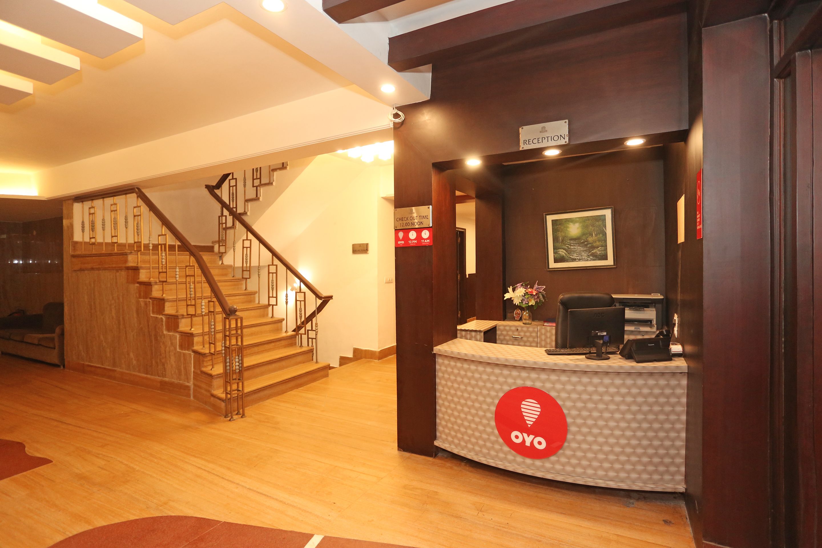 A reception area with a wooden staircase, a reception desk, and a sign indicating check-in times.