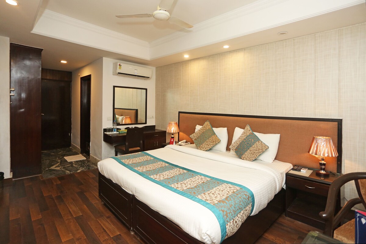 A hotel room with a large bed, bedside tables, a desk, and a chair.
