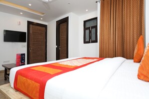 A hotel room with a large bed, a flat-screen TV, two doors, and a window with curtains. - OYO 11583 Hotel Prime View (New Delhi)