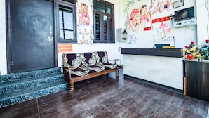 Een receptiezone met een houten bank, een receptiebalie, een aan de muur bevestigde televisie en een muurschildering.