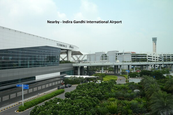 An airport terminal with a modern design, featuring a large glass facade and a prominent overpass.