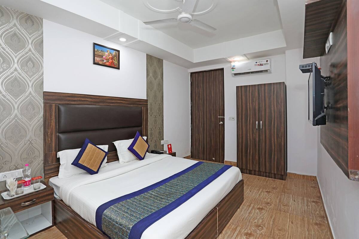 Une chambre d’hôtel avec un grand lit, une table de chevet, un téléviseur fixé au mur et une armoire.