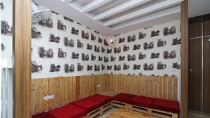 Une pièce avec des bancs en bois et une table, un mur orné de motifs et un ventilateur au plafond.