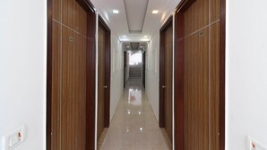 Un couloir avec des portes en bois, numérotées 306 et 305, qui mène à un escalier.