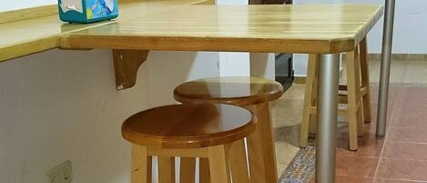 A kitchen with wooden stools, a countertop, and tiled flooring.