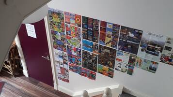 A staircase with a wooden handrail and a wall decorated with various posters and flyers.