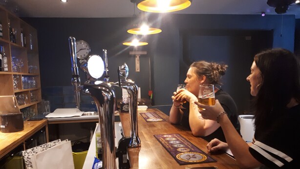 Een bar met een houten toonbank, biertaps en een klok.