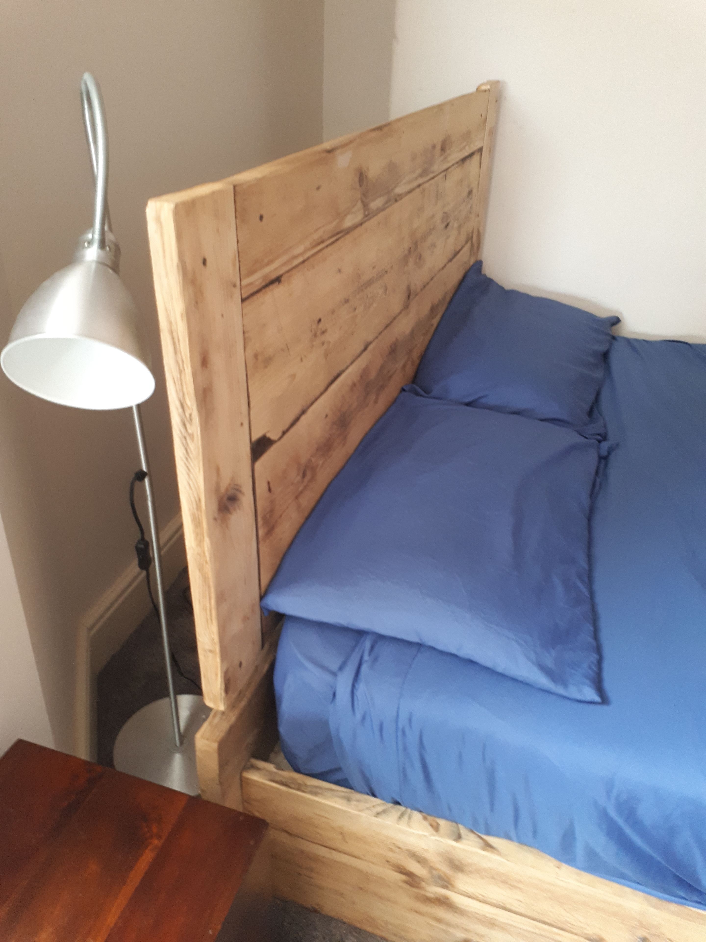 A wooden bed with blue bedding, a metal lamp, and a wooden nightstand.
