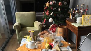 A breakfast table set with various food items, a Christmas tree, and a bottle of wine in the background. - Bed & Breakfast Il Carignano (Cagliari)