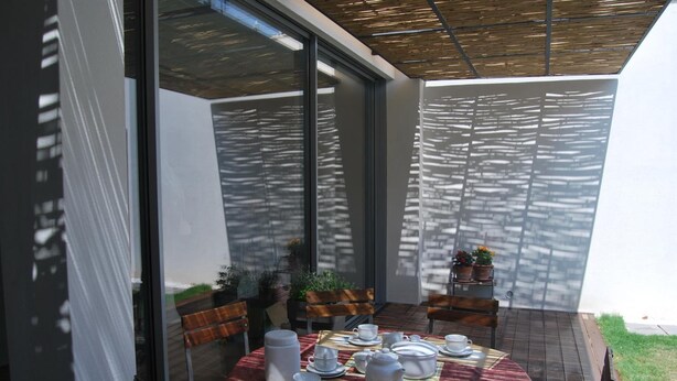 A dining area with a round table set for a meal, surrounded by chairs, and a glass partition. - Bed & Breakfast Il Carignano (Cagliari)