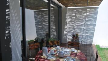 A dining area with a round table set for a meal, surrounded by chairs, and a glass partition.