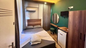 A hotel room with a bed, a desk, a wardrobe, an air conditioning unit, and a television. - Yakamoz Pansiyon (Antalya)