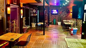 A restaurant with wooden flooring, tables, chairs, and a TV mounted on the wall. - Yakamoz Pansiyon (Antalya)