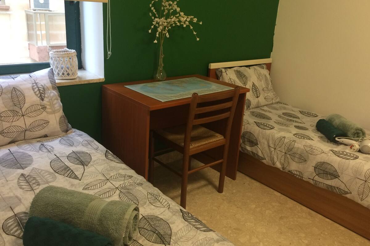 Ein Zimmer mit zwei Betten, einem Holztisch und einer grünen Wand.