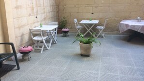A patio area with a table and chairs, a potted plant, and a small grill. - Maltese Rooms (Sliema)