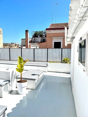 A rooftop terrace with a potted plant, white walls, and a metal fence. - Saint Patrick B&B Guesthouse (Barletta)