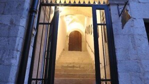 Una escalera de piedra que conduce a un arco con una puerta de metal.