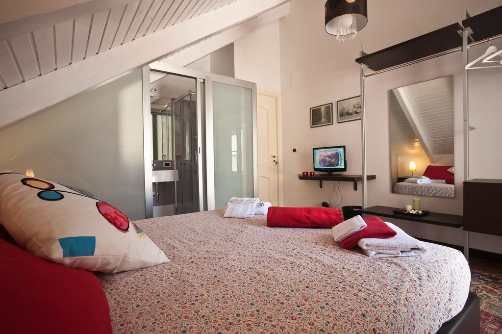 Une chambre à coucher comprenant un lit, une télévision, un miroir et une porte donnant sur une salle de bain.