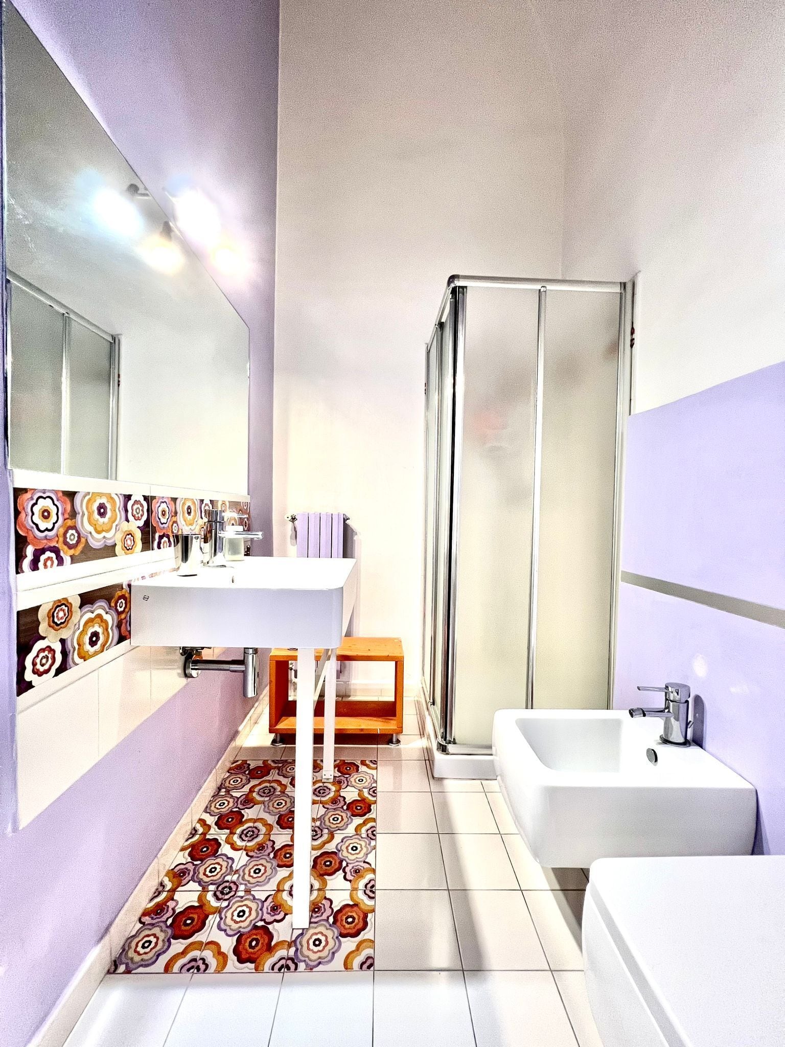 A modern bathroom with a white sink, mirror, and shower.