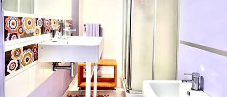 A modern bathroom with a white sink, mirror, and shower.