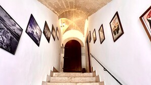 Una escalera conduce a una puerta oscura, flanqueada por cuadros en las paredes.
