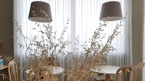 Un comedor con dos mesas redondas, sillas y plantas decorativas altas.