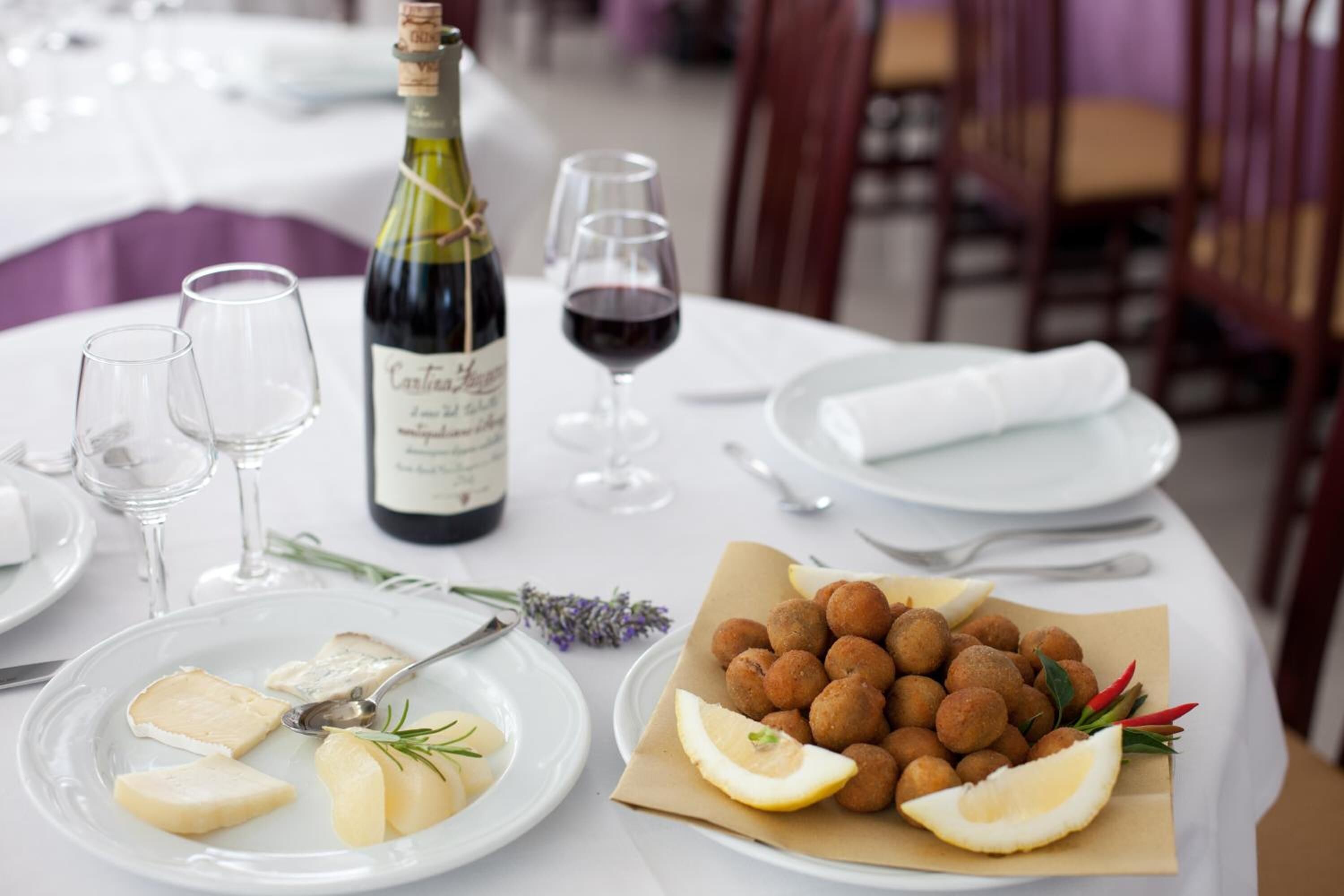 Een gedekte tafel met kaas, een fles wijn en een bordje kroketten.