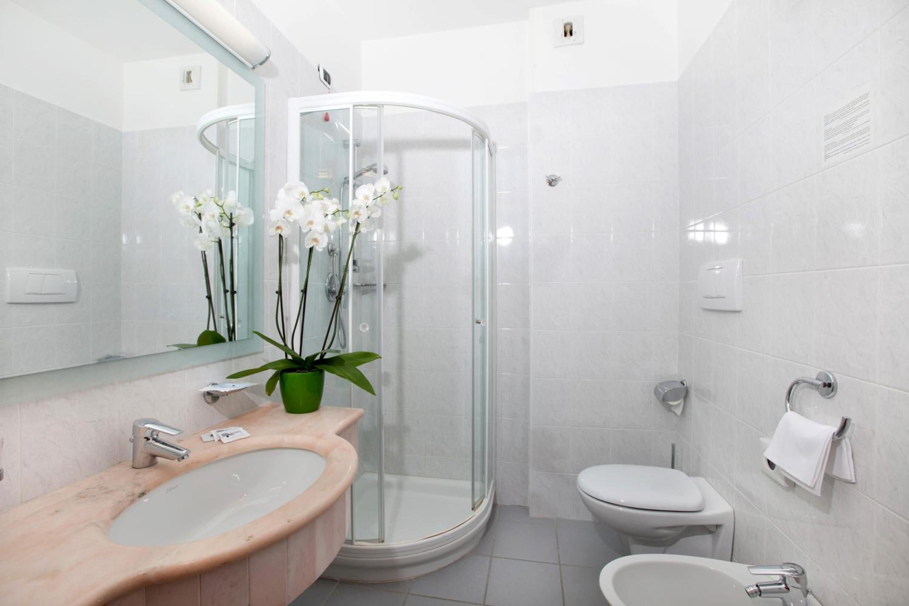 A modern bathroom with a glass-enclosed shower, a sink, a toilet, and a bidet.