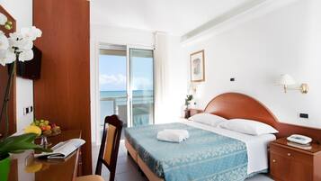 Una camera d'albergo con un letto, un comodino, una sedia, una scrivania con una pianta, una finestra con vista e una porta.